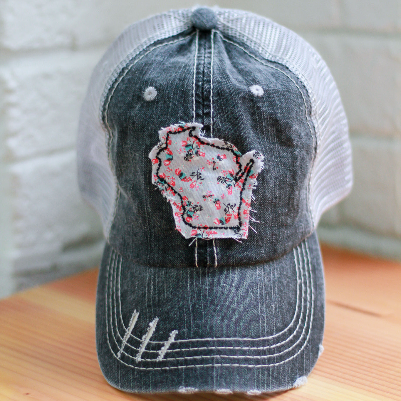 gray distressed trucker hat with gray floral raggy patch in the shape of Wisconsin