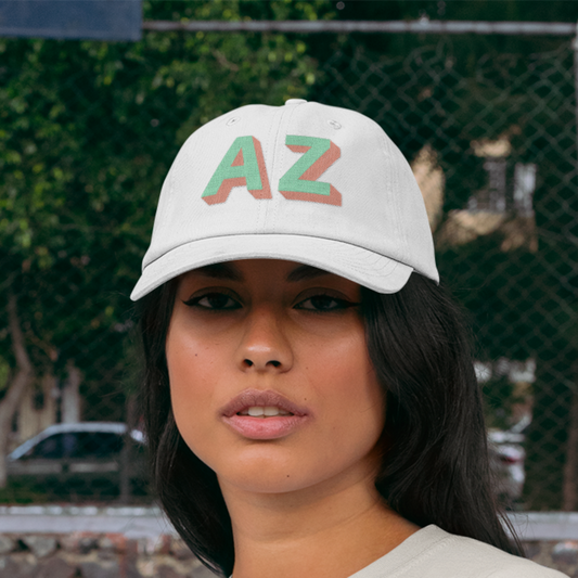 Woman wearing white dad style hat with AZ in aqua and coral shadow block font